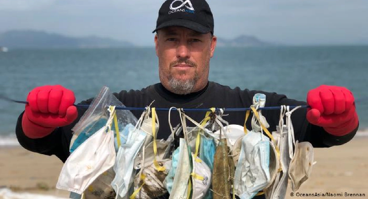 Défenseur de l'environnement tenant des masques venus s'échouer sur des îles Soko