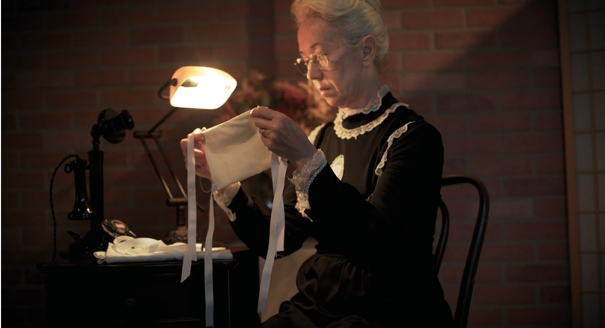 Woman at sewing table with light