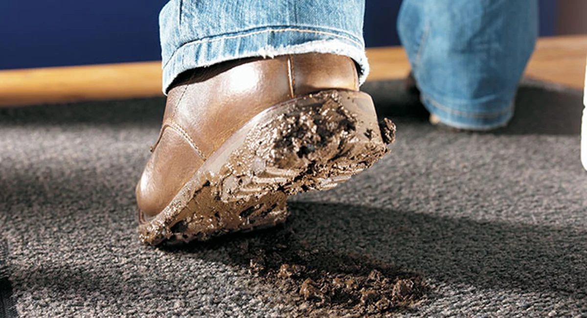 chaussure boueuse laissant de la terre sur un tapis