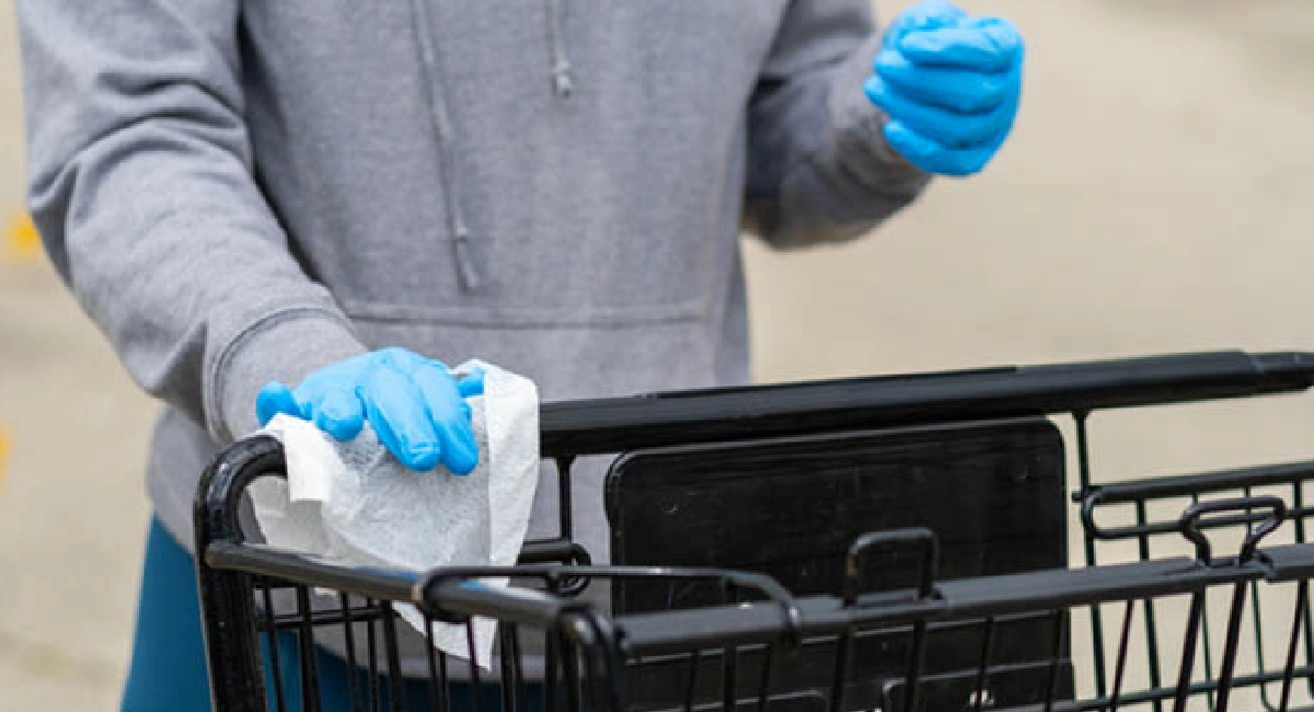 Personne poussant un caddy de supermarché avec des gants jetables