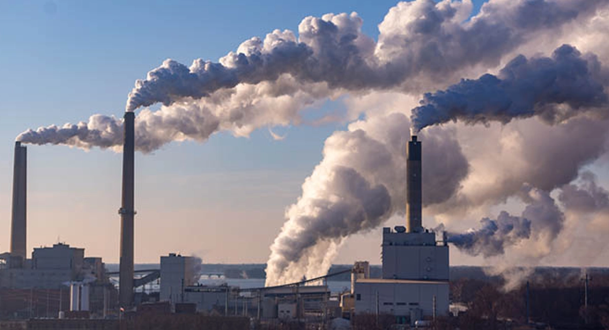 vent soufflant la pollution rejetée par les cheminées d'une usine