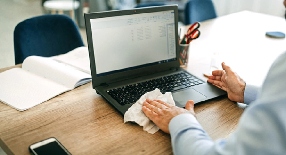Homme nettoyant le clavier d'un ordinateur portable