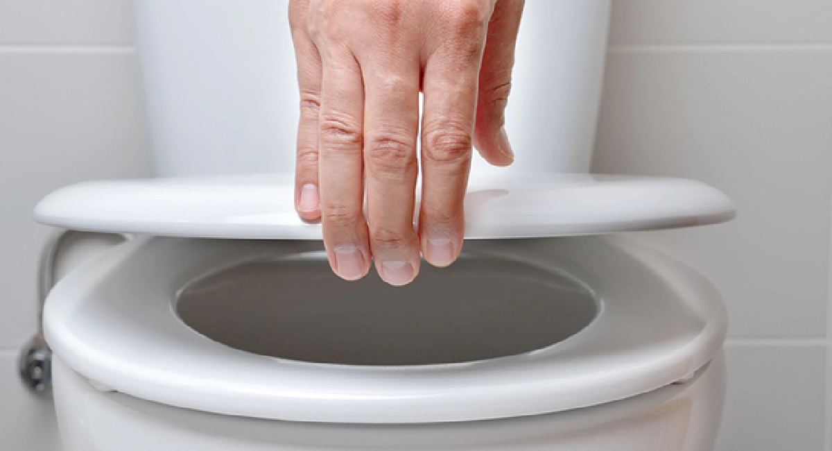Homme refermant le couvercle de toilettes